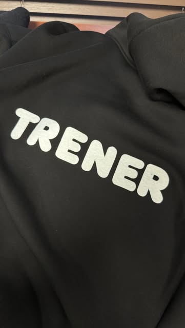 Czarna bluza z napisem TRENER, uszyta w pracowni Malleaa
